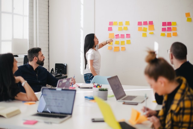 Woman placing sticky notes on wall in business meeting